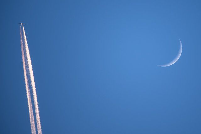 (210614) -- BRUSSELS, June 14, 2021 (Xinhua) -- Photo taken on June 13, 2021 shows a plane flying past the crescent moon in Brussels, Belgium. (Xinhua\/Zhang Cheng