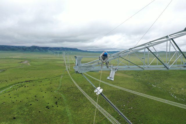 (210724) -- XINING, July 24, 2021 (Xinhua) -- A staff member of the State Grid Corporation Qinghai Branch works on the Qinghai-Henan UHV DC power transmission line in Henan Mongolian Autonomous County of Huangnan Tibetan Autonomous Prefecture, northwest China\