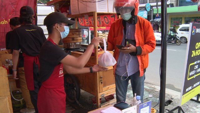 (211110) -- JAKARTA, Nov. 10, 2021 (Xinhua) -- An app-based motorcycle taxi driver takes the food order at a food stall selling steamed dim sums in East Jakarta, Indonesia, Nov. 8, 2021. TO GO WITH: Feature: "Selling dim sums in Indonesia" - more young Indonesians start Chinese food businesses amid pandemic (Photo by Guruh Dwi Riyanto\/Xinhua