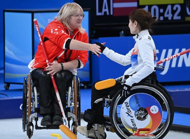 (220306) -- BEIJING, March 6, 2022 (Xinhua) -- Francoise Jaquerod (L) of Swtizerland shakes hands with Baek Hyejin of South Korea during the Wheelchair Curling Round Robin Match between Switzerland and South Korea of Beijing 2022 Paralympic Winter Games at National Aquatics Center in Beijing, capital of China on March 6, 2022. (Xinhua\/Ren Chao