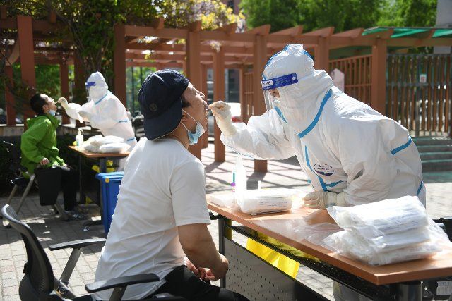 (220426) -- BEIJING, April 26, 2022 (Xinhua) -- A medical worker takes a swab sample from a citizen at a makeshift nucleic acid testing site during a mass testing for COVID-19 in Haidian District, Beijing, capital of China, April 26, 2022. Beijing will conduct three rounds of nucleic acid testing in 11 areas from Tuesday to Saturday in efforts to curb the risk of COVID-19, local authorities said at a press conference Monday. The testing will cover people in the districts of Xicheng, Dongcheng, Haidian, Fengtai, Shijingshan, Fangshan, Tongzhou, Shunyi, Changping, Daxing and Beijing Economic-Technological Development Area, said Xu Hejian, spokesperson of the municipal government of Beijing. (Xinhua\/Ren Chao