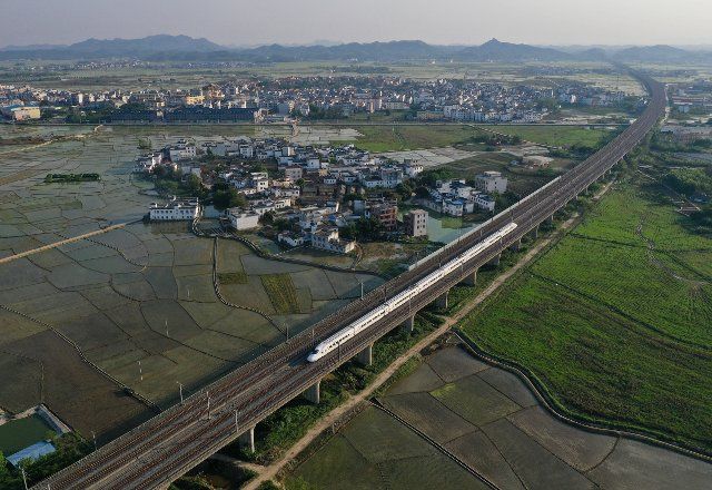 (220405) -- NANNING, April 5, 2022 (Xinhua) -- In this aerial photo, a high-speed train runs on the bridge above fields in Binyang County, south China\