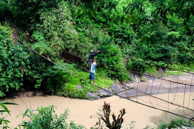 (220625) -- CIANJUR, June 25, 2022 (Xinhua) -- People hold wires to cross a river at Salam Nunggal village in Cianjur district, West Java, Indonesia, on June 25, 2022. Locals have to cross the river with the help of wires as there is no proper bridge over the river. (Photo by Septianjar\/Xinhua