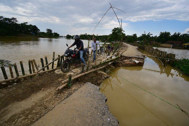 (220630) -- NAGAON, June 30, 2022 (Xinhua) -- A motorcyclist crosses a temporary bamboo footbridge as a portion of a road was washed away due to flood following heavy rainfall in Nagaon district of India\