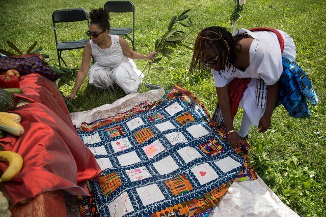 (220621) -- NEW YORK, June 21, 2022 (Xinhua) -- Chayanne Marcano (L) and Catherine Mbali Green-Johnson, curators of the quilt project, place a quilt memorializing victims of the COVID-19 pandemic during the 13th Annual Juneteenth Festival in Prospect Park in the Brooklyn borough of New York, the United States, on June 19, 2022. Participants made artworks or wrote words on the quilts in commemoration of their family members who died of the coronavirus. As African Americans in New York joined others from across the country to commemorate the end of slavery in the United States, they also honored the lives lost to the COVID-19 pandemic at a regular thematic event in Prospect Park, Brooklyn. TO GO WITH "Feature: New Yorkers honor lives lost to COVID-19 at Juneteenth celebration" (Photo by Michael Nagle\/Xinhua