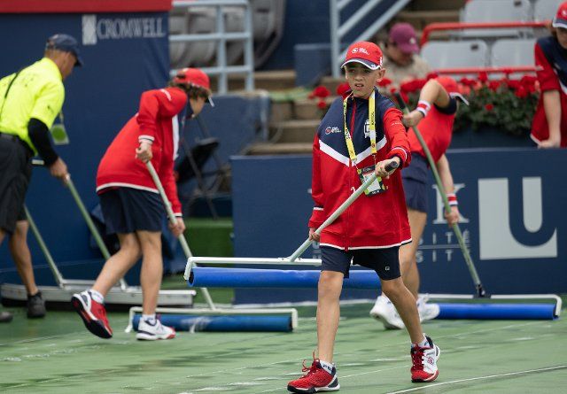 (220809) -- MONTREAL, Aug. 9, 2022 (Xinhua) -- Staff members and volunteers try to keep the court dry after rain in the IGA Stadium in Montreal, Canada on Aug. 8, 2022. (Photo by Andrew Soong\/Xinhua