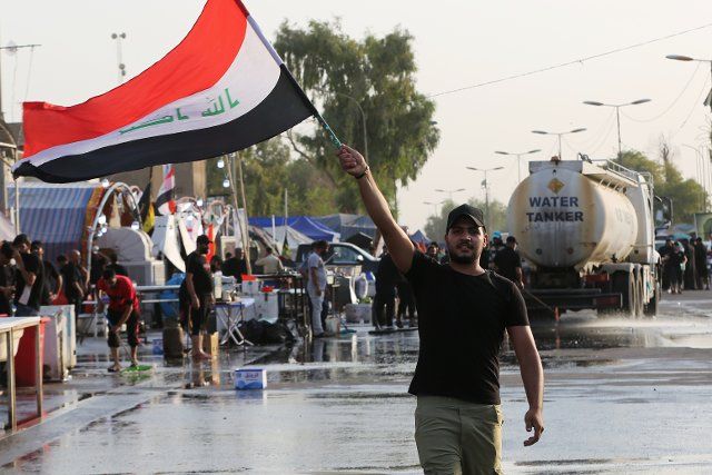 (220810) -- BAGHDAD, Aug. 10, 2022 (Xinhua) -- A protester wields an Iraqi flag during protests by followers of Shiite cleric Moqtada al-Sadr in Baghdad, Iraq on Aug. 8, 2022. Amid a protracted political stalemate in Iraq, the followers of powerful Shiite cleric Moqtada al-Sadr have vowed to continue holding protests in Baghdad until their demands for comprehensive reforms and anti-corruption fight are met. TO GO WITH "Feature: Iraq\