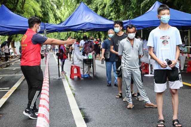 (220811) -- HAIKOU, Aug. 11, 2022 (Xinhua) -- Khan Muhammad Hashir Shahid (1st L), a volunteer from Pakistan, guides local residents at a nucleic acid sampling site in Haikou, capital of south China\