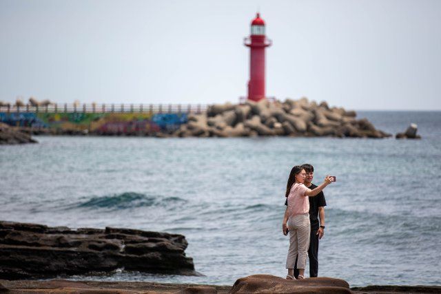 (220716) -- JEJU, July 16, 2022 (Xinhua) -- Tourists take selfies at the seaside in Jeju, South Korea, July 16, 2022. (Xinhua\/Wang Yiliang