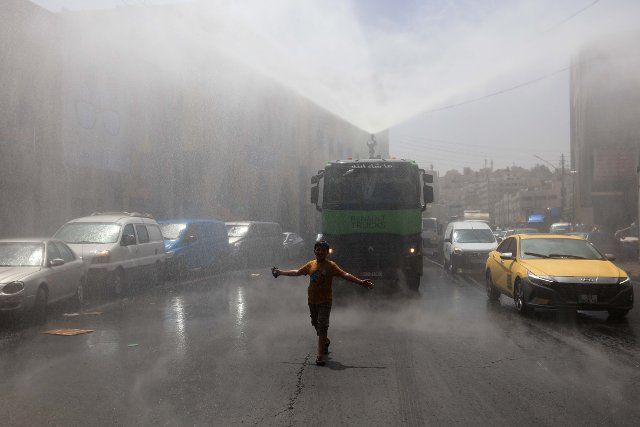 (220829) -- AMMAN, Aug. 29, 2022 (Xinhua) -- A boy cools off in a spray of water from a water truck during a heatwave in Amman, Jordan, on Aug. 28, 2022. Jordan\