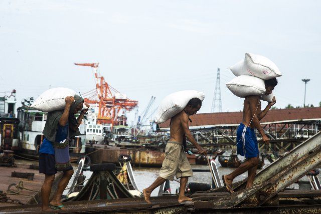 (220811) -- YANGON, Aug. 11, 2022 (Xinhua) -- Workers carry bags of rice at a jetty in Yangon, Myanmar, on Aug. 11, 2022. Myanmar\