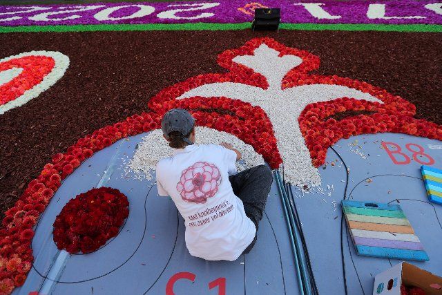 (220812) -- BRUSSELS, Aug. 12, 2022 (Xinhua) -- A woman prepares the flower carpet at the Grand Place in Brussels, Belgium, Aug. 12, 2022. After the cancellation of the Flower Carpet 2020 due to the COVID-19 pandemic, the traditional festival returned to Brussels from August 12 to 15, 2022. The theme of the Flower Carpet 2022 is "50th Anniversary of the Brussels Flower Carpet". Artists reinterpret the design of the pattern of the first flower carpet in 1971, using about 140,000 begonias, 225,000 dahlias, dyed bark, rolls of turf, chrysanthemums and euonymus. (Xinhua\/Zheng Huansong
