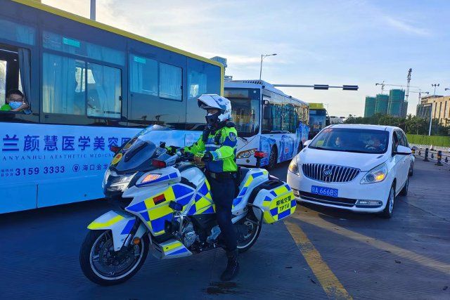 (220819) -- HAIKOU, Aug. 19, 2022 (Xinhua) -- A traffic police officer, also a member of the service team, escorts stranded tourists to a port in Haikou, south China\