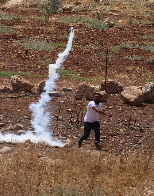 (220819) -- NABLUS, Aug. 19, 2022 (Xinhua) -- A protester throws back a tear gas canister fired by Israeli soldiers during clashes following a protest against the expansion of Jewish settlements in the West Bank village of Beit Dajan, east of Nablus, Aug. 19, 2022. (Photo by Nidal Eshtayeh\/Xinhua