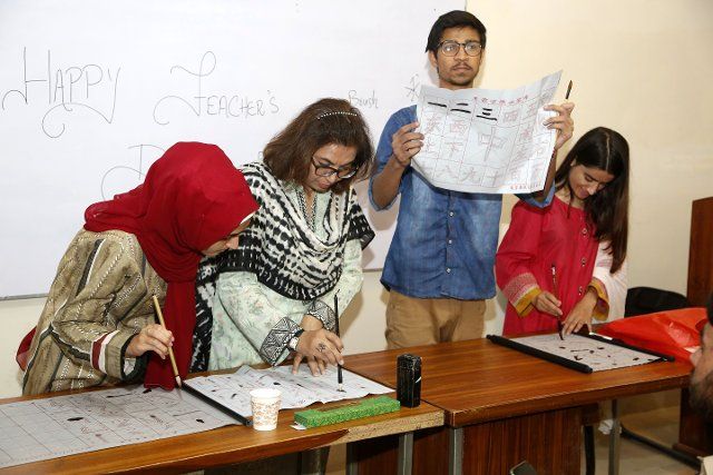 (221005) -- ISLAMABAD, Oct. 5, 2022 (Xinhua) -- Students learn Chinese calligraphy during a Chinese language class in Islamabad, capital of Pakistan, on Oct. 5, 2022. (Xinhua\/Ahmad Kamal) TO GO WITH Feature: Pakistan\