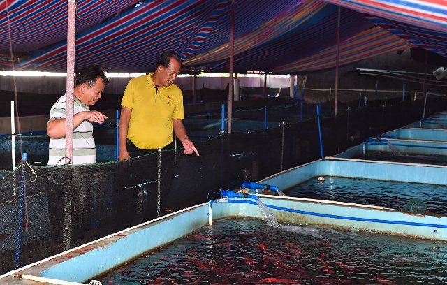 (221006) -- HAIKOU, Oct. 6, 2022 (Xinhua) -- Wang Shumao (R) visits an aquaculture farm in Tanmen Village of Tanmen Township in Qionghai, south China\