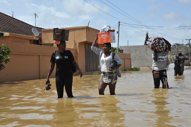 (221006) -- ACCRA, Oct. 6, 2022 (Xinhua) -- People wade through a flooded street in Accra, Ghana, on Oct. 5, 2022. Thousands of residents of the southwestern part of Accra, the Ghanaian capital, have been displaced due to the spillage of the Weija Dam. The spillage of the dam was caused by excess water following torrential rains over the weekend, which contributed to the water level behind the dam rising above the maximum level. The dam built on the Densu River is the source of potable water for more than half of the 5.4 million population of the national capital. (Photo by Seth\/Xinhua