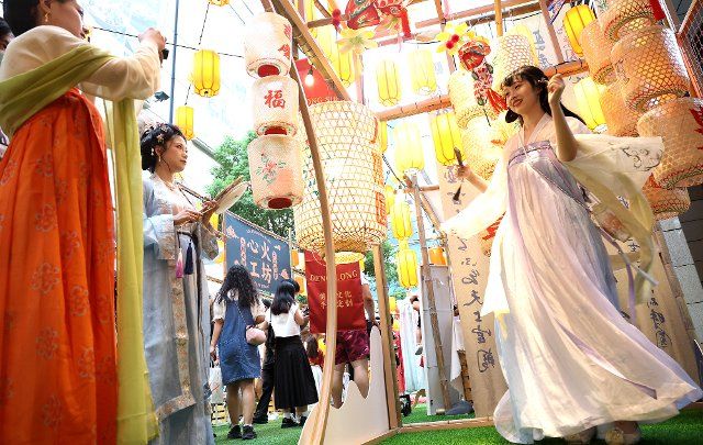 (221001) -- BEIJING, Oct. 1, 2022 (Xinhua) -- A tourist wearing Hanfu, a type of traditional Chinese garment, poses for photos with Mid-Autumn Festival lanterns as backdrop in east China\