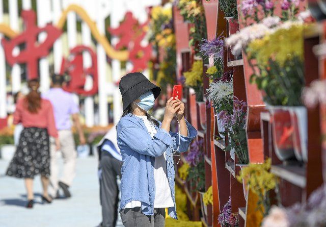 (221001) -- YINCHUAN, Oct. 1, 2022 (Xinhua) -- A citizen takes photos of flowers at a flower expo park in Yinchuan, northwest China\