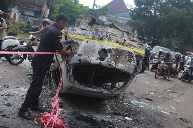 (221002) -- MALANG, Oct. 2, 2022 (Xinhua) -- A police officer ties a rope on the wreckage of a burned car outside the Kanjuruhan Stadium in Malang of East Java province, Indonesia, Oct. 2, 2022. At least 129 people were killed and 180 others injured after a stampede and clashes at a football match in Indonesia\