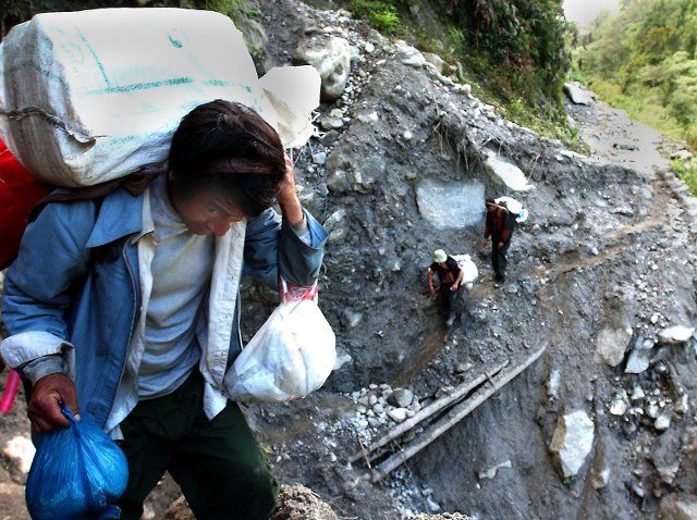 (221002) -- LHASA, Oct. 2, 2022 (Xinhua) -- File photo shows porters carrying goods through a landslide area to Medog County, southwest China\